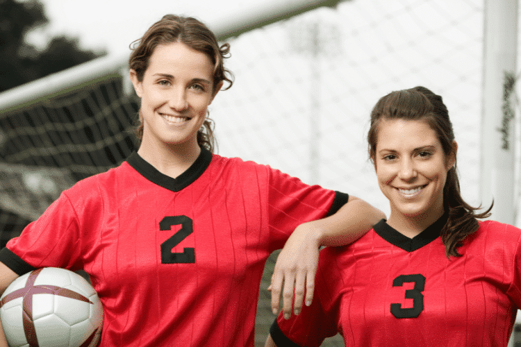 Smiling female soccer players wearing red shirts