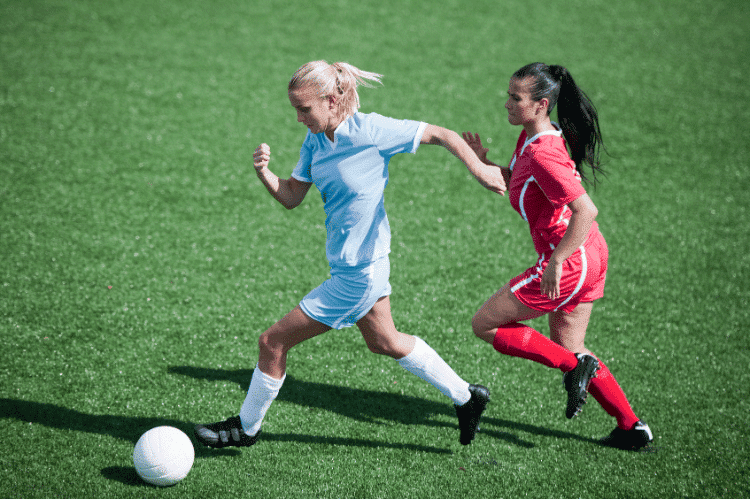 Two female footballers competing for the ball