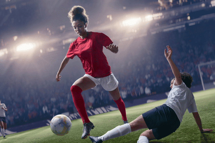 Professional woman soccer player jumping over sliding tackle during match