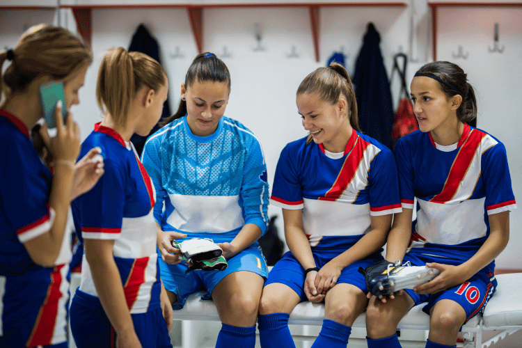 Team of happy female football players relaxing in a locker room