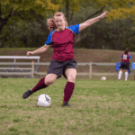 Female Soccer player kicking the ball