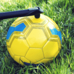 Inflating Soccer Ball with Manual Pump on Green Grass