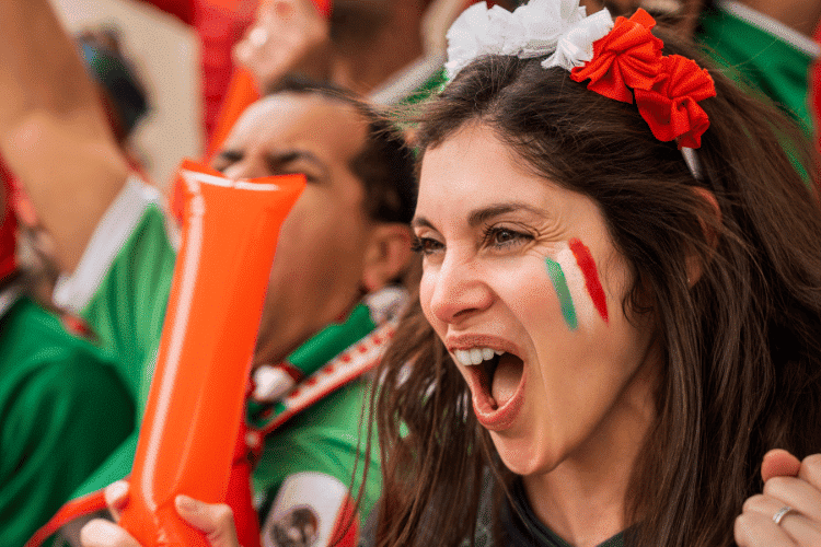Young woman with painted face screaming goal during football match
