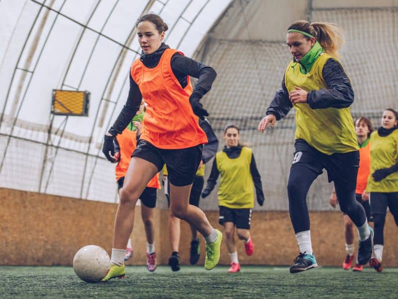 women playing recreational soccer indoors